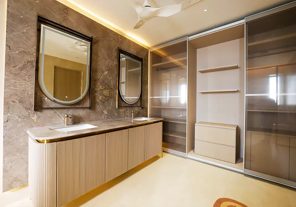 Vanity with fluted drawers next to glass-front wardrobes